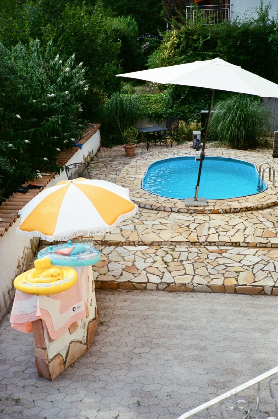 Small pool with a yellow umbrella set into a stone patio.