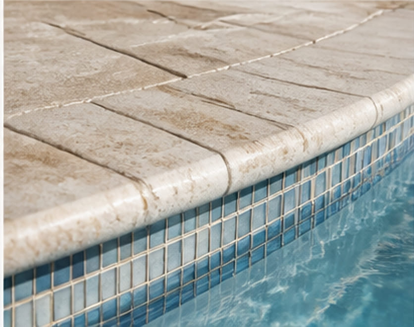 Close view of travertine coping meeting blue glass waterline tile.